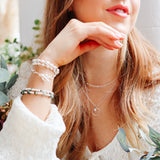 Girl wearing sterling silver stacking bracelets with emerald gemstones. Birthstone bracelet for March.