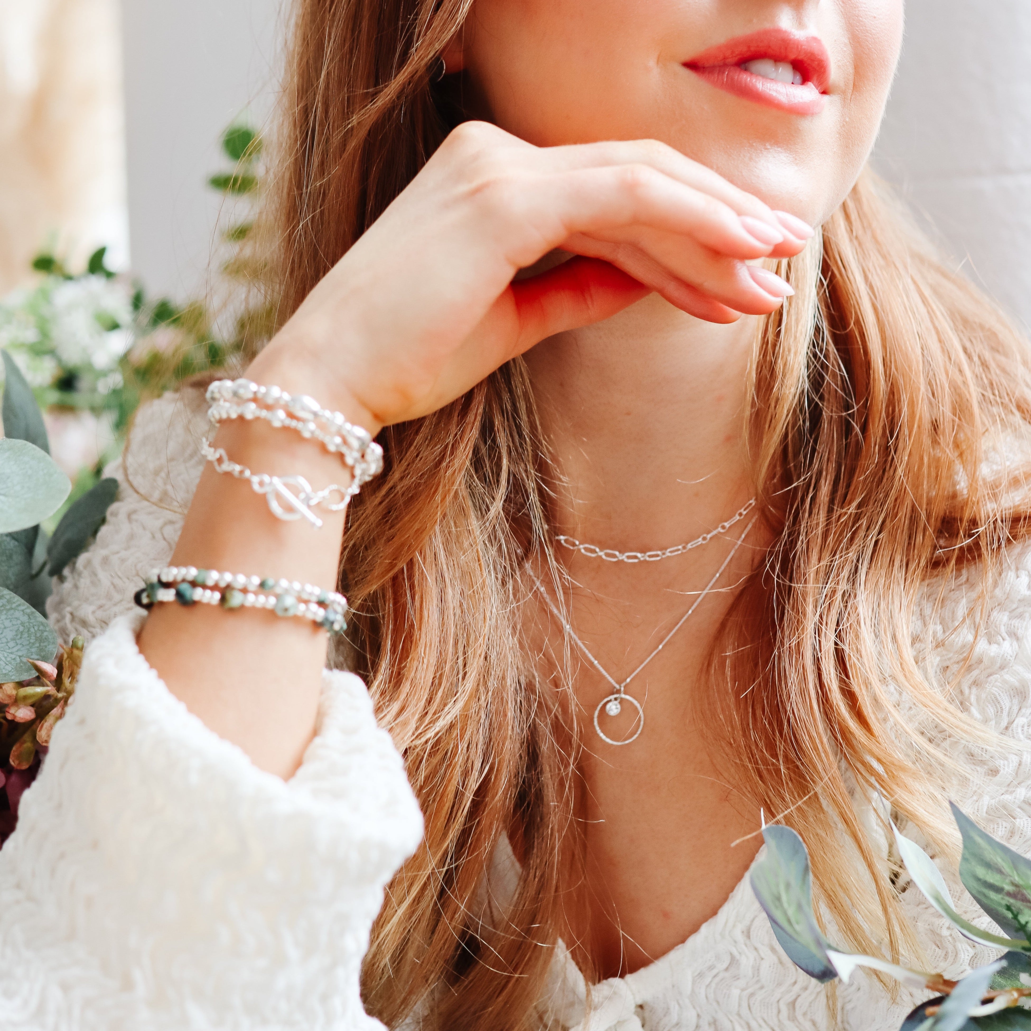 Girl wearing sterling silver stacking bracelets with emerald gemstones. Birthstone bracelet for March.