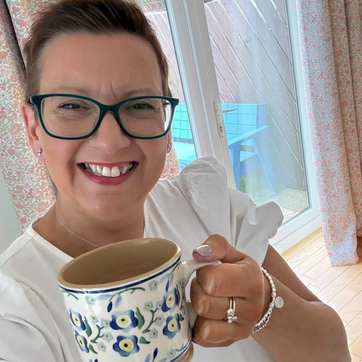 Laura smiling at home, wearing her sterling silver forget me not bracelet