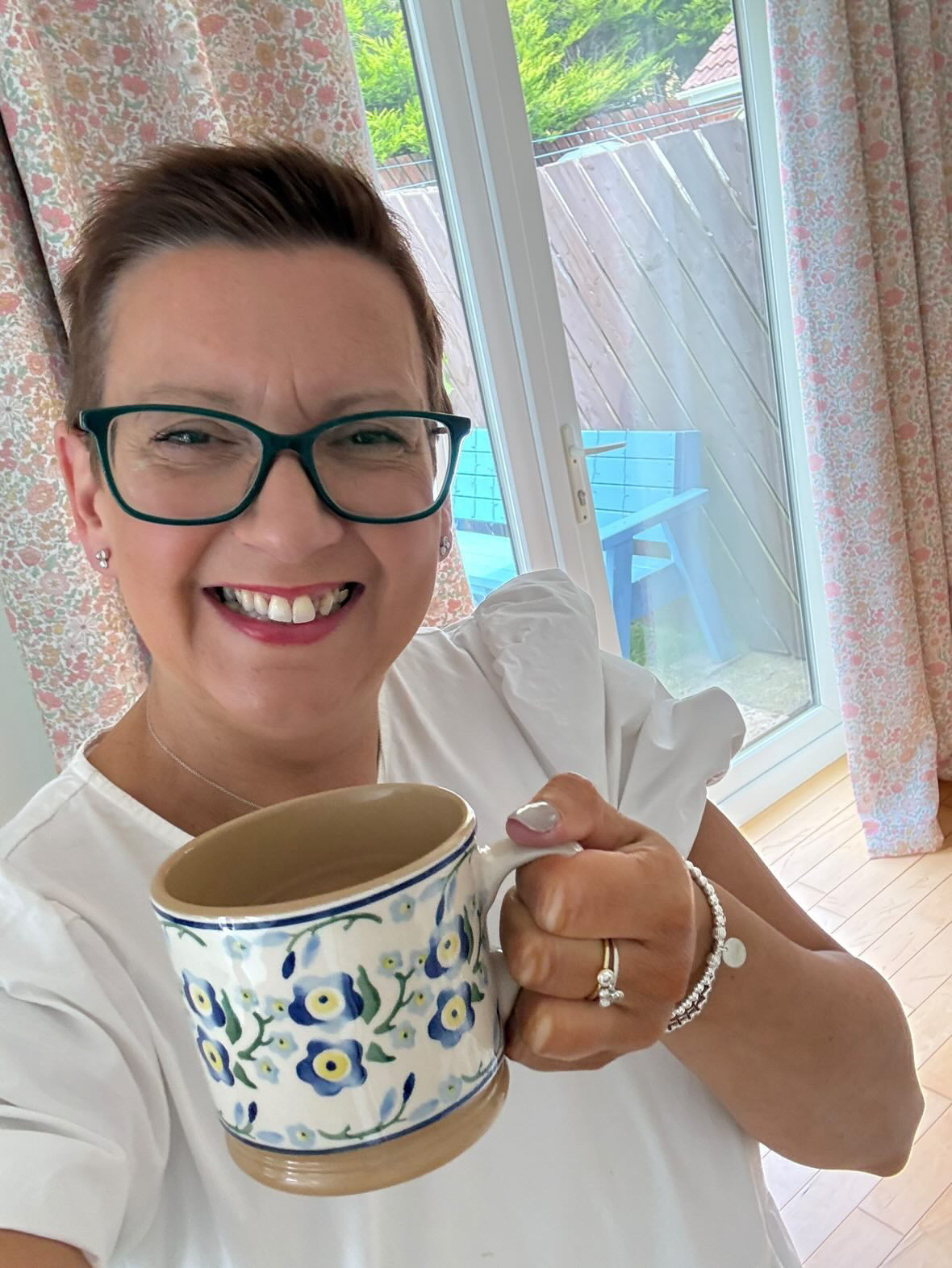 Laura smiling at home, wearing her sterling silver forget me not bracelet