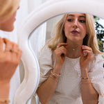 Woman adjusting jewelry in front of a mirror