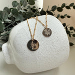 Necklace displayed on a white textured stand with green leaves in the background